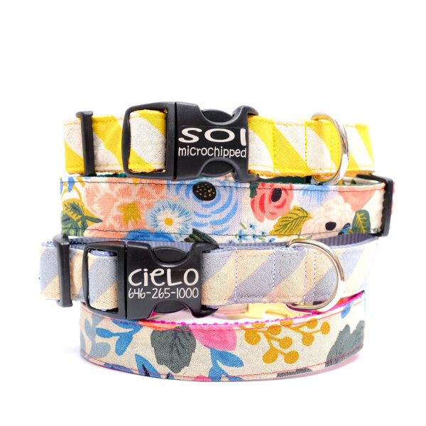 Stack of colorful canvas dog collars from Mimi Green in various patterns and sizes, customizable with engraved buckles